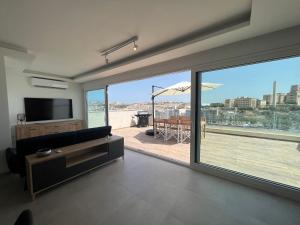 a living room with a large window and a view of a deck at Ta Xbiex Sea Front Penthouse in Taʼ Xbiex