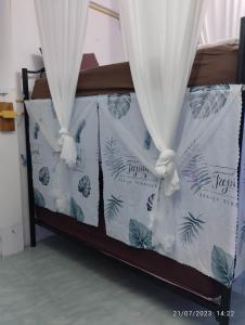 Una cama con cortinas blancas y plantas. en Phangan Hostel Haadrin Homestay, en Haad Rin