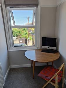 a desk with a computer on it in front of a window at Walpole House sleeps 19-24 in Margate