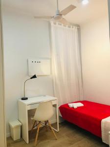 a bedroom with a desk and a bed with a red sheet at Sant Jordi Pisos - Dos de Maig in Barcelona