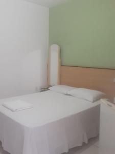 1 cama blanca con sábanas y almohadas blancas en una habitación en Hotel Flamboiã, en Araraquara