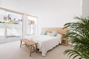 biała sypialnia z łóżkiem i rośliną w obiekcie Bossa Bay Suites with Private Pool - MC Apartments Ibiza w mieście Ibiza +37 zdjęć
