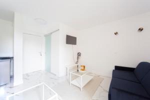 ein weißes Wohnzimmer mit einem blauen Sofa und einem TV in der Unterkunft Studio - Luxury Home in Bussy-Saint-Georges