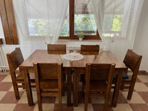 una mesa de comedor de madera con sillas y ventanas en Roua Muntelui, en Sărata-Monteoru