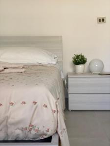 a white bedroom with a bed and a night stand at Casa Chicchina in Senigallia
