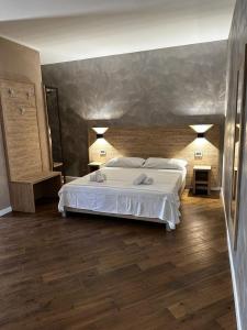 a bedroom with a large white bed and wooden floors at Casa Catone (affitta camere) in Monte Porzio Catone