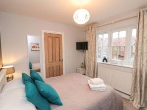 a bedroom with a bed with blue pillows and a window at The Beach Retreat in Filey