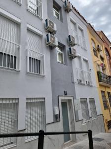 a gray building with windows and a door at Apartamentos ZANCA CITY CENTER in Málaga