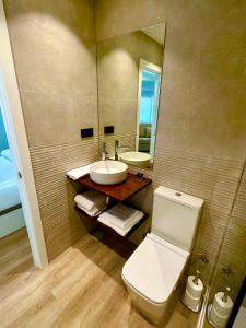 ein Badezimmer mit einem WC, einem Waschbecken und einem Spiegel in der Unterkunft Apartamentos Sunsets Málaga Centro in Málaga