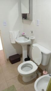 La salle de bains est pourvue de toilettes blanches et d'un lavabo. dans l'établissement Mi hogar, es tu hogar., à San Martín