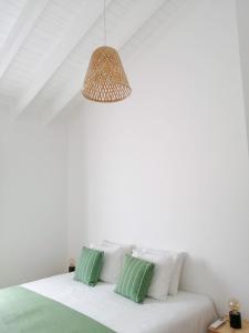 a white room with a bed with green and white pillows at Terreiro Ocean House - Unique Seaside Escape in São Roque