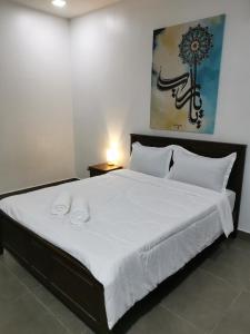 a bedroom with a large bed with white sheets at NK HOMESTAY DESARU in Bandar Penawar