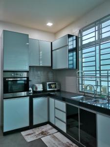 a kitchen with white cabinets and black counter tops at NK HOMESTAY DESARU in Bandar Penawar