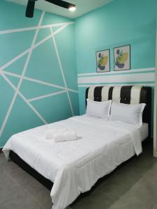 a bedroom with a large white bed with blue walls at NK HOMESTAY DESARU in Bandar Penawar