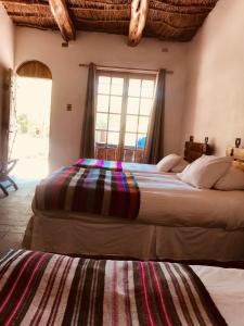 two beds in a room with a window at Hotel La Aldea in San Pedro de Atacama