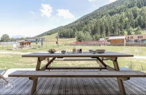 a picnic table on a deck with a view of a field at La Norma en Terrasse in Villarodin-Bourget