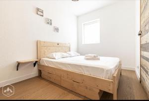 - une chambre avec un lit en bois dans une pièce dotée d'une fenêtre dans l'établissement La Norma en Terrasse, à Villarodin-Bourget
