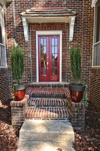 シャーロットにあるThe Home Collection CLT: Kirkwood Avenueの赤い扉と鉢植えの植物が2つあるレンガ造りの家