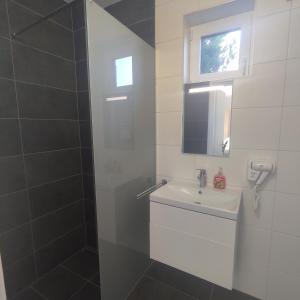 a white bathroom with a sink and a mirror at Horváth Apartman in Fertőd