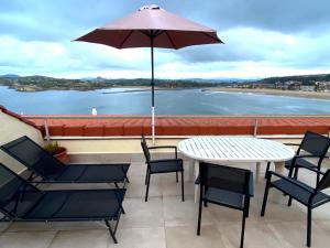 a patio with a table and chairs and an umbrella at Playa de los Locos con Garaje in Suances