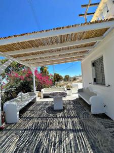 une terrasse avec des canapés, une table et une pergola dans l'établissement Santorini Style Rooms, à Vóthon