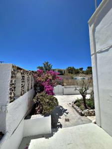 een wit gebouw met bloemen aan de zijkant bij Santorini Style Rooms in Vóthon