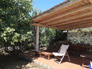 pérgola de madera con silla, mesa y banco en Deliziosa Porzione di Casale, en Pescia Romana