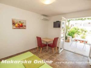 een kamer met een tafel en stoelen en een patio bij Apartman Nikolić 2 in Makarska