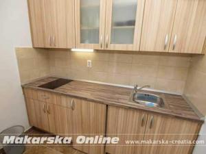een keuken met een wastafel en houten kasten bij Apartman Nikolić 2 in Makarska