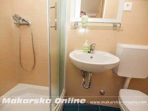 een badkamer met een wastafel, een toilet en een douche bij Apartman Nikolić 2 in Makarska