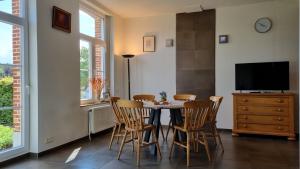 uma sala de jantar com uma mesa e cadeiras e uma televisão em Boshovense Velden em Grobbendonk