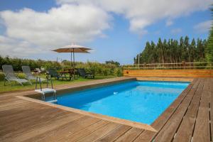 a swimming pool with a wooden deck and an umbrella at Quinta do Sol in Lourinhã