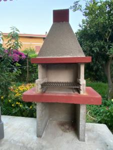 un horno de ladrillo con capota roja en un jardín en L'INCOGNITA, en San Nicolò dʼArcidano