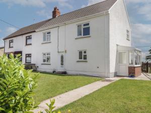 a white house with a lawn in front of it at Ty Beca in Clynderwen