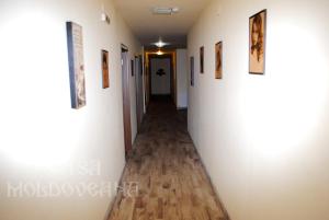 einen Flur mit weißen Wänden, Holzböden und Bildern in der Unterkunft Pensiunea CASA MOLDOVEANA in Piatra Neamţ