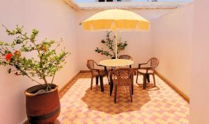 a dining room with a table and chairs and an umbrella at Maison de la Lagune in Oualidia