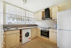 a kitchen with wooden cabinets and a washer and dryer at 3Bed Apartment Pimlico London in London