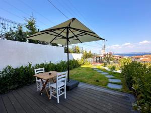 a table and chairs with an umbrella on a deck at Oikos Bozcaada in Bozcaada