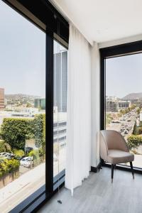a chair sitting in a room with large windows at The Godfrey Hotel Hollywood in Los Angeles