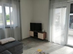 een woonkamer met een tv en een bank bij Apartman Sterpin in Pula