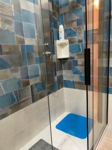 een douche met een glazen deur en een blauwe tegelmuur bij L'INCOGNITA in San Nicolò dʼArcidano