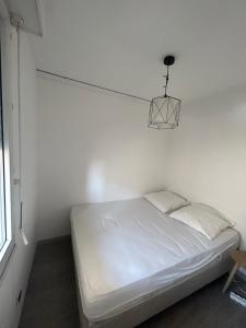 Dormitorio blanco con cama y lámpara en Appartement cosy au cœur de Sète avec balcon détente, en Sète 10 fotos más