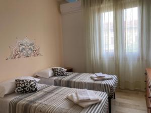 een kamer met 2 bedden en een raam met gordijnen bij L'INCOGNITA in San Nicolò dʼArcidano