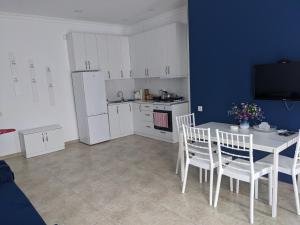 cocina con armarios blancos, mesa y sillas en Blue Apartment, en Gonio