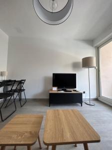 Una sala de estar con un televisor y una mesa. en Appartement cosy au cœur de Sète avec balcon détente, en Sète