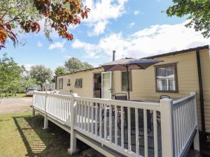 a mobile home with a white fence and an umbrella at 14 Larch View in Lincoln