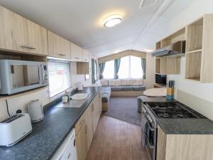 a kitchen with a stove and a living room at 14 Larch View in Lincoln