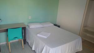a small bedroom with a white bed and a desk at Hotel Flamboiã in Araraquara