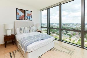 a bedroom with a white bed and large windows at The Canary Wharf Place - Stunning 2BDR Flat in London