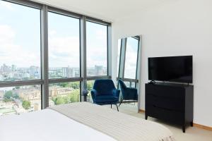 a bedroom with a bed and a flat screen tv at The Canary Wharf Place - Stunning 2BDR Flat in London